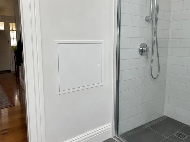 Neat wall access panel beside a tiled shower in a home bathroom in Drummoyne